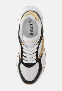Weiße Sneaker mit einem Mesh-Obermaterial, schwarzen Lederakzenten mit einem goldenen Kettendetail und "GUESS"-Branding auf der Zunge.
