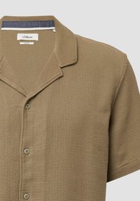 Bruine kortebloemige shirt met een textuurstof, voorzien van een notch-kraag en drie knopen aan de voorkant, met een subtiel patroon.