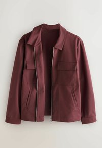 Burgundy jacket with a smooth texture, zip closure, two front pockets, and a wide collar. The design features long sleeves and a relaxed fit.