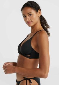 Zwarte bikini-top met een driehoekig ontwerp, dunne verstelbare bandjes en uitsnijdingen. Gemaakt van zachte, rekbare stof.