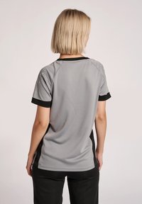 Grijze sportshirt met korte mouwen, voorzien van zwarte accenten en gestructureerde patronen op de schouders, gemaakt van ademend materiaal.