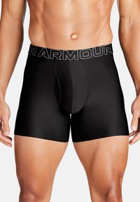Schwarze Boxer-Briefs mit einem strukturierten Bund, auf dem "UNDER ARMOUR" in Weiß steht. Der Stoff ist glatt und elastisch und sorgt für eine enganliegende Passform.