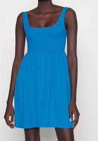 Blaues ärmelloses Kleid mit eckigem Ausschnitt, tailliertem Bund und ausgestelltem Rock. Hergestellt aus glattem Baumwollstoff in einfarbiger Ausführung ohne Muster.