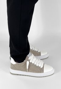 Heren sneakers met een lichtbruine suède bovenkant, witte leren neuskap, dikke witte veters en een gestructureerde zool. Geschikt voor casual gebruik.