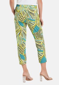 Musterhafte Capri-Hosen mit einem lebhaften Design in Türkis, Gelb und Schwarz, das Blatt- und geometrische Motive zeigt. Elastischer Bund, cropped Länge.