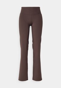 Hnědé, vysoké, rozšířené jogger kalhoty vyrobené z elastického materiálu s hladkým povrchem, s malým černým logem Nike na pásku.