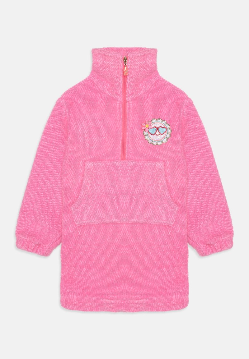 Robe en polaire rose avec un col montant, une fermeture éclair à mi-hauteur, une poche avant et un écusson décoratif représentant un visage souriant avec des cœurs et des fleurs.