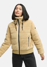 Beige gefütterte Jacke mit weicher, strukturierter Oberfläche, hohem Kragen, schwarzem Reißverschluss und Kordelzügen. Verfügt über gerippte Bündchen und einen gerippten Saum.
