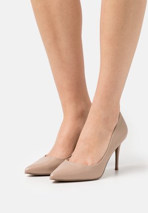 Bombas de tacón alto beige con diseño de punta afilada y textura de cuero suave. Presenta un tacón de aguja delgado.