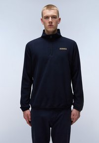 Pullover de forro polar ligero en azul marino con media cremallera, que presenta un pequeño parche de logo en el pecho. Textura suave y mangas largas.