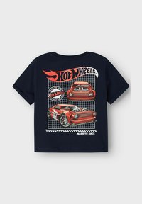 Tumši zila īsām piedurknēm T-krekls ar sarkaniem Hot Wheels automobiļu grafikas attēliem, režģa fona un baltu tekstu "VEIDOTS SACENSĪBĀM."