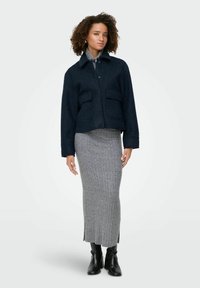 Mornarsko plava teksas jakna s ovratnikom, prednjim džepovima i zakopčavanjem na gumbe, uparena sivi rebrasti midi suknju i crnim gležnjačama.