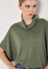 Haut à col bénitier en vert pâle, fabriqué en tissu tricoté à côtes. Caractéristiques : coupe ample et manches larges, associé à un jean.
