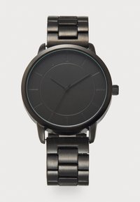 Black metal watch with a round case, matte finish, and minimalist design. The dial features thin hour markers and smooth hands. Metal link bracelet.