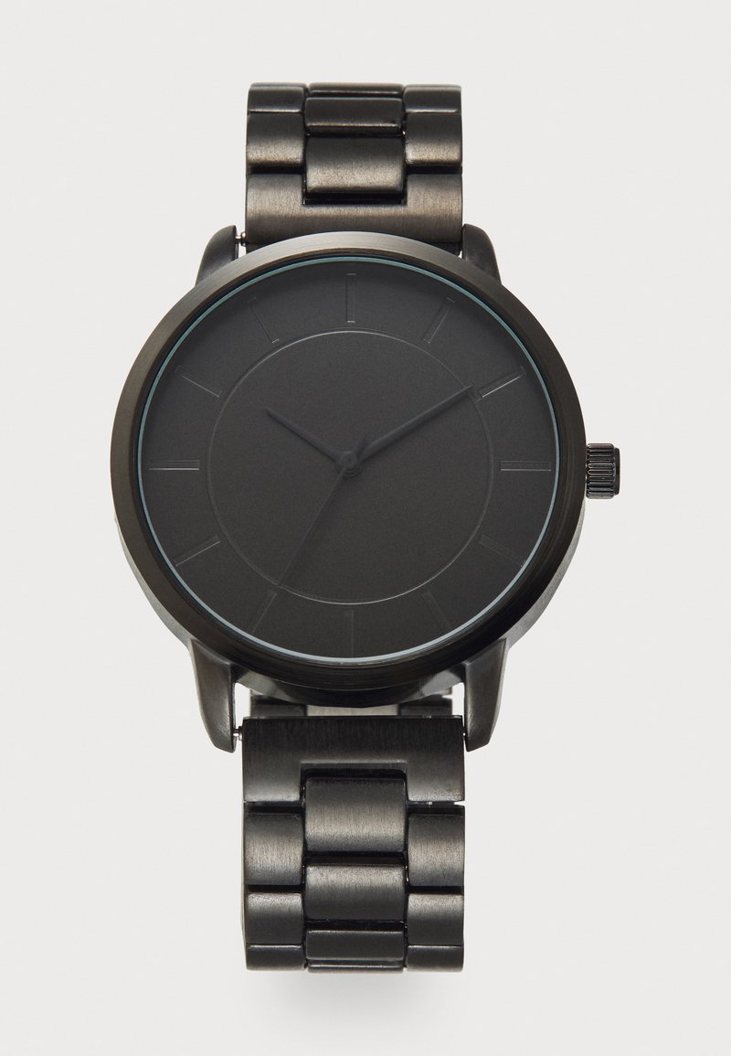 Black metal watch with a round case, matte finish, and minimalist design. The dial features thin hour markers and smooth hands. Metal link bracelet.