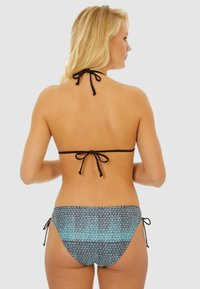 Maillot de bain bikini avec un lien autour du cou noir et des liens latéraux ajustables. Le bas présente un motif géométrique bleu sur un fond sombre. Texture lisse.