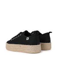 Zapatos de lienzo negros con una suela de plataforma de cuerda de yute. Presenta ojales metálicos y una pequeña etiqueta de logo en el costado.