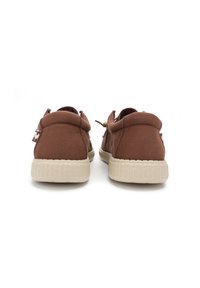 Brown canvas shoes with rounded backs, featuring a beige textured rubber sole and a looped pull tab on the heel for easy fitting.