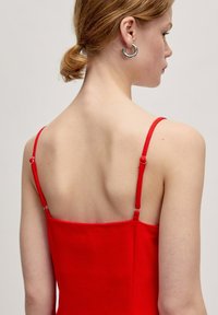 Rotes ärmelloses Kleid mit dünnen Trägern und verstellbarem Zubehör. Glatte Textur, körperbetonte Silhouette und quadratischer Ausschnitt.