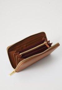 Portefeuille en cuir marron avec une finition texturée, fermeture éclair dorée, plusieurs emplacements pour cartes et un compartiment zippé, mettant en valeur un intérieur rouge.