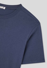 Granatowa bawełniana koszulka z okrągłym dekoltem, krótkimi rękawami i gładką fakturą; posiada metkę z oznaczeniem rozmiaru 'S' wewnątrz kołnierza.