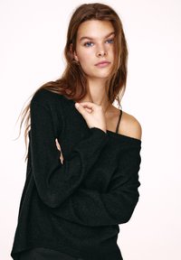 Czarny sweter dziany z odkrytymi ramionami i długimi rękawami. Miękka faktura i luźny fason, doskonale uzupełniające minimalistyczny styl.