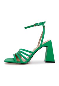 Sandal de tacón alto de charol verde, con punta cuadrada, múltiples tiras superpuestas y un tacón ancho con un acento negro en la base.