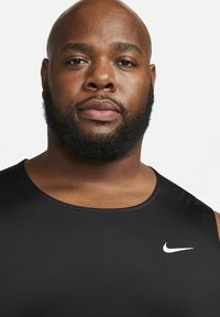 Must värviline sportlik tank top ümmarguse kaelusega ja valge Nike logo rinnal. Kanga pind näeb välja siledana ning see on sobiva siluettiga.