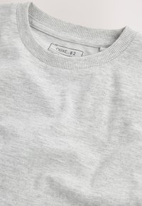 Grå crewneck-tröja i mjukt tyg, med ribbad krage och subtil textur, med en etikett där det står "next.82."