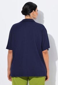 Navyblauw short-sleeve shirt met een ontspannen pasvorm, zonder opvallende details, en een kraag aan de achterkant, gecombineerd met groene broek.