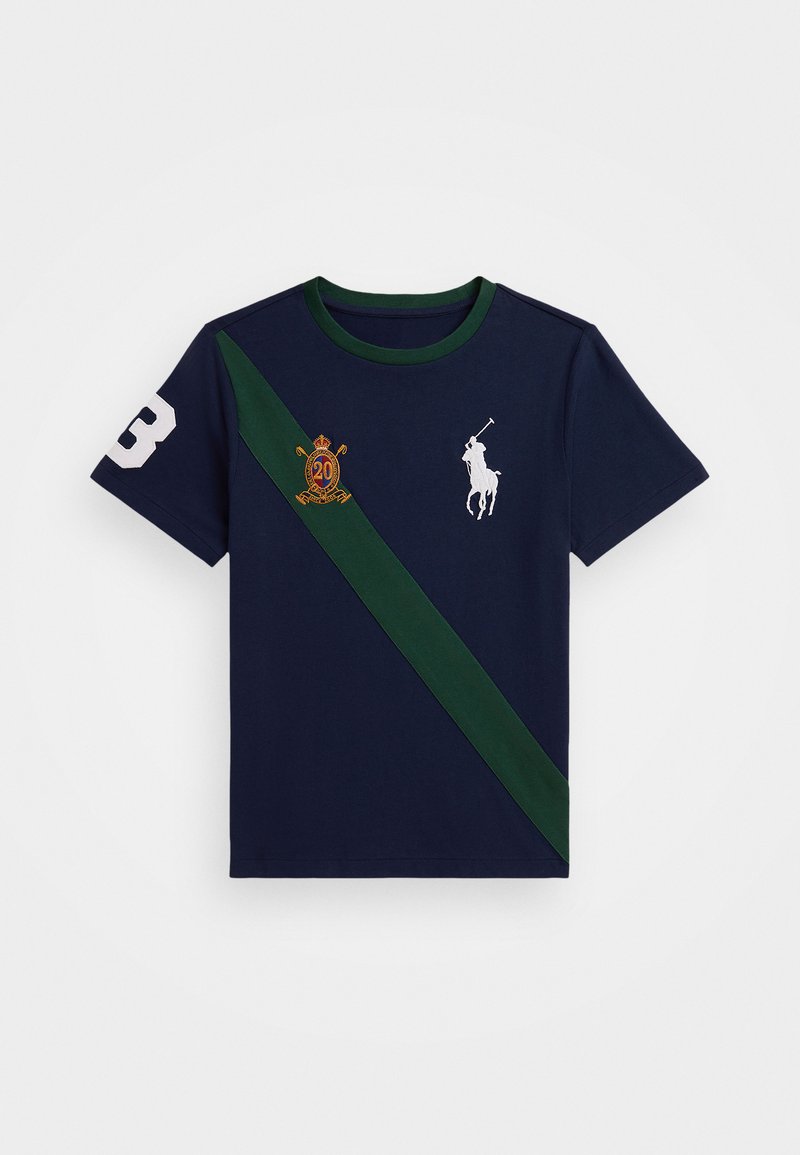 T-shirt en coton marine avec une bande diagonale verte, un logo de polo blanc, un blason brodé et le chiffre '3' blanc sur la manche gauche.