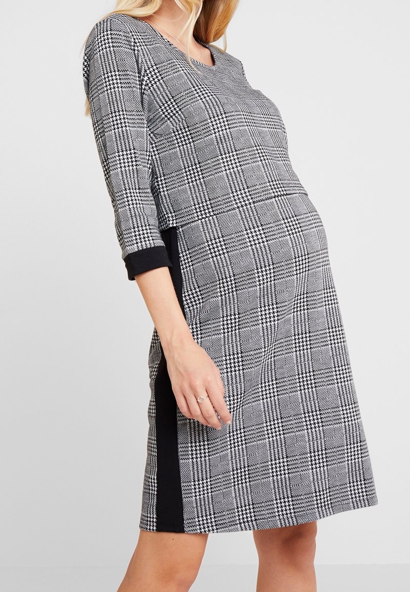 Svart och vit rutig klänning med trekvartsärmar, rund halsringning och svarta sidopaneler. Mjuk tygkvalitet och avslappnad passform.