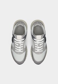 Baskets gris et blanches en mesh et daim, semelle en caoutchouc épaisse, lacets ronds et accents de logo sur les côtés et la languette.