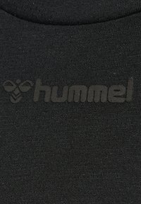 Czarna tkanina z delikatnie wytłoczonym logo "hummel" oraz symbolem pszczoły, umieszczonymi na środku klatki piersiowej ubrania.