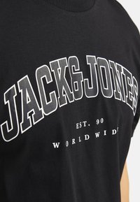Sorte bomulds t-shirt med fed hvid tekst "JACK & JONES" og "EST. 90 WORLDWIDE" i forskellige skriftstørrelser. Rund hals.