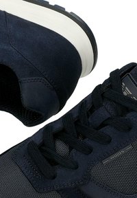 Granatowe buty sportowe z mieszanką zamszu i siateczki, z teksturowanymi sznurowadłami i wyściełaną białą podeszwą.