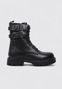 Botte de combat noire en cuir avec un laçage à l'avant, des boucles réglables doubles sur la tige et une semelle en caoutchouc texturée.