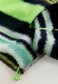 Tissu en polaire douce avec des rayures vertes, noires, blanches et bleues, doté d'un cordon de serrage vert et d'un verrouillage sur le bord.