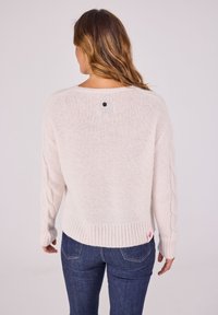 Hellrosa Strickpullover mit Kabelstrick-Ärmeln, rundem Ausschnitt, geripptem Saum und einem kleinen schwarzen Knopfdetail auf der Rückseite.