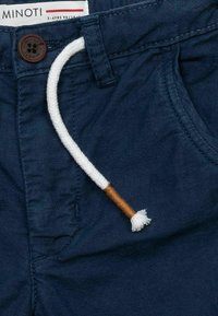 Marinblå barnshorts gjorda av mjukt tyg med en frampocket, vit snörning med trädetalj och synlig varumärkesetikett.