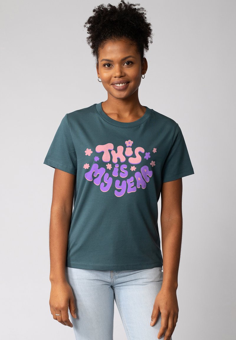 Türkisfarbene BaumwollT-Shirt mit Rundhalsausschnitt und kurzen Ärmeln, bedruckt mit buntem Text: "DAS ist MEIN JAHR" und floralen Akzenten.