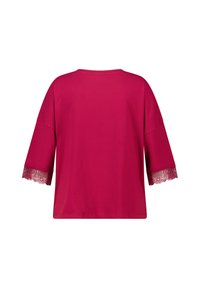 Helder roze top met driekwart mouwen en kantafwerking op de mouwranden, weergegeven vanaf de achterkant op een witte achtergrond.