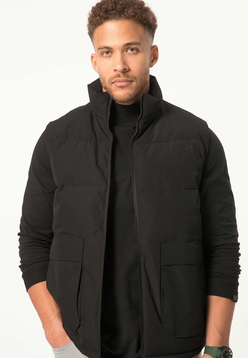 Gilet puffo nero con colletto alto, zip frontale e due grandi tasche a toppa. Tessuto liscio, materiale leggero e design aderente.