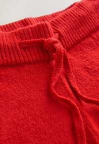 Rode gebreide sweatpants met een geribbelde elastische tailleband en een trekkoord. Zachte textuur, egale kleur en licht pluizige stof.