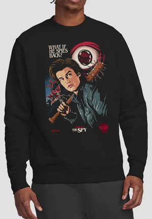 Junger Mann hält einen mit Stacheln besetzten Baseballschläger, umgeben von fliegenden roten Kreaturen und Blut, mit dem Text "Was, wenn er zurückspioniert?" und dem Titel "The Spy".