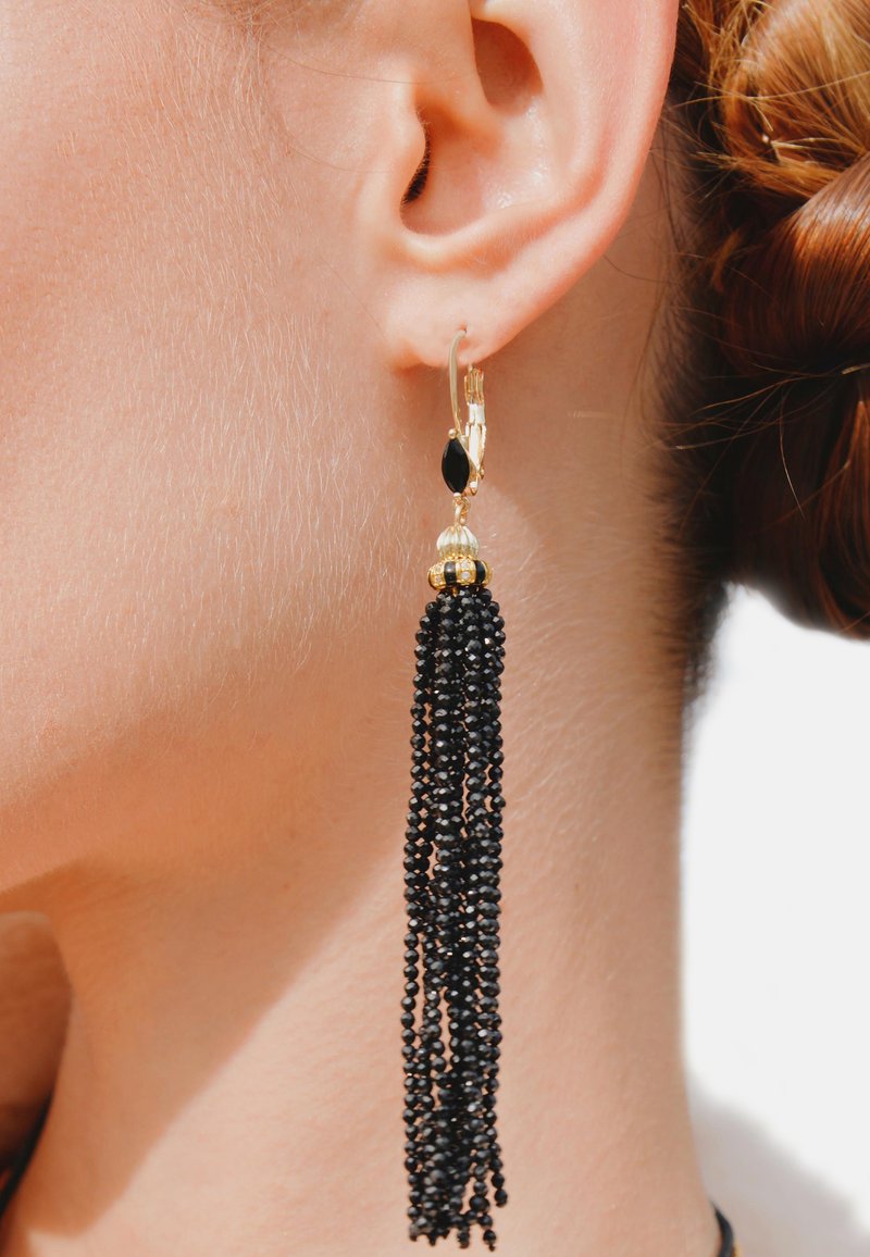 Boucles d'oreilles en or avec des franges en perles noires. Présente un accent en forme de goutte d'eau noire et une perle dorée texturée au-dessus des franges.