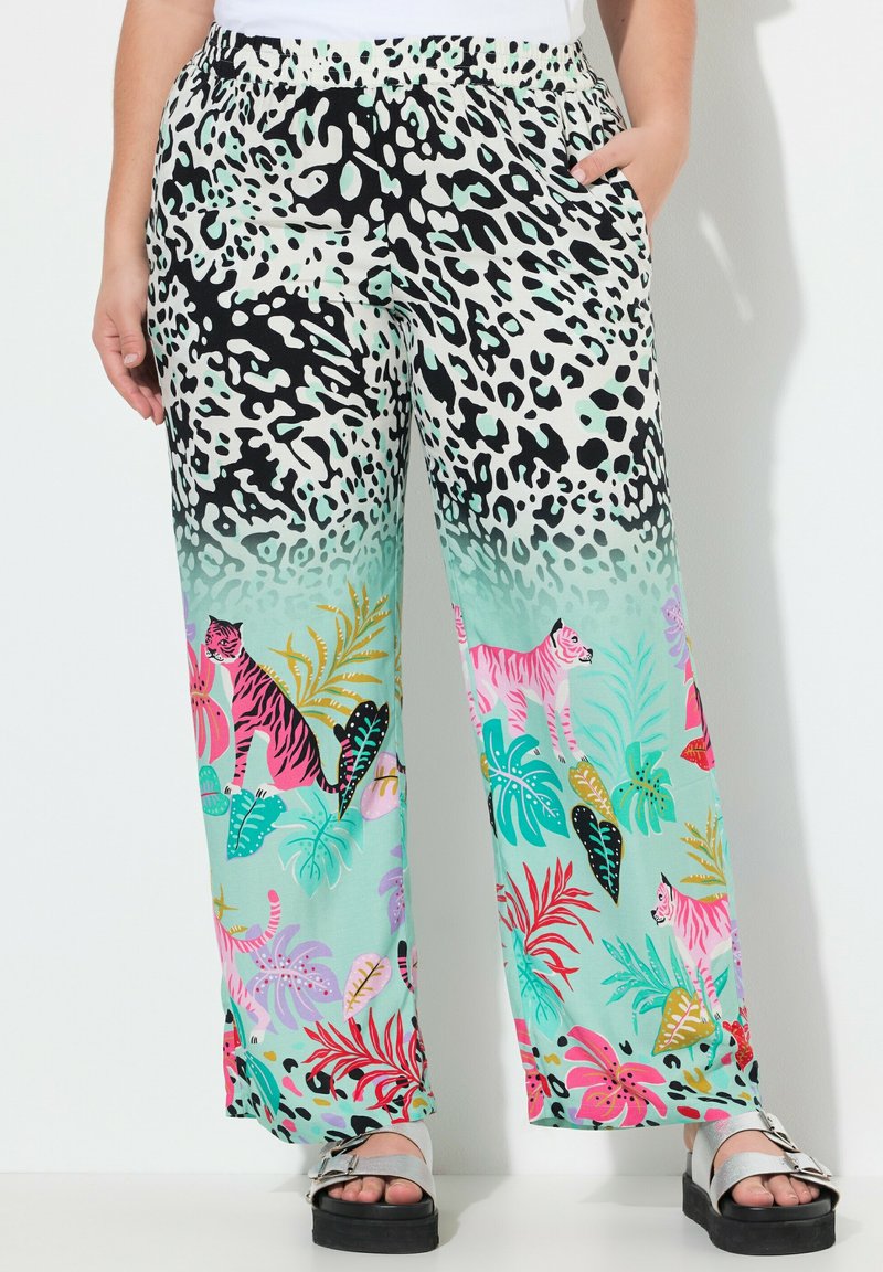 Lichte, gemusterde broek met wijde pijpen heeft een gradiënt van zwart-witte dierenprint naar kleurrijke tropische bladeren, met tijgers en heldere bloemen.