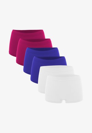 Red fitted crop top and high-waisted shorts made of stretchy material. Model sits on a soft, round platform against a neutral background.