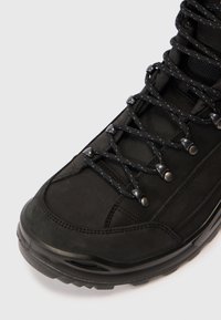 Zwarte wandelschoen met een stevige rubberen zool, bovenwerk van suede en nylon, metalen oogjes en gestructureerde veters voor extra grip en ondersteuning.