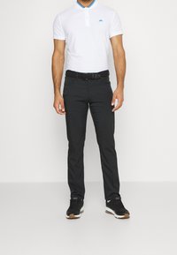 Bílá polokošile s modrými detaily na límci, kombinovaná s černými slim-fit kalhotami a černými teniskami s gumovou podrážkou.